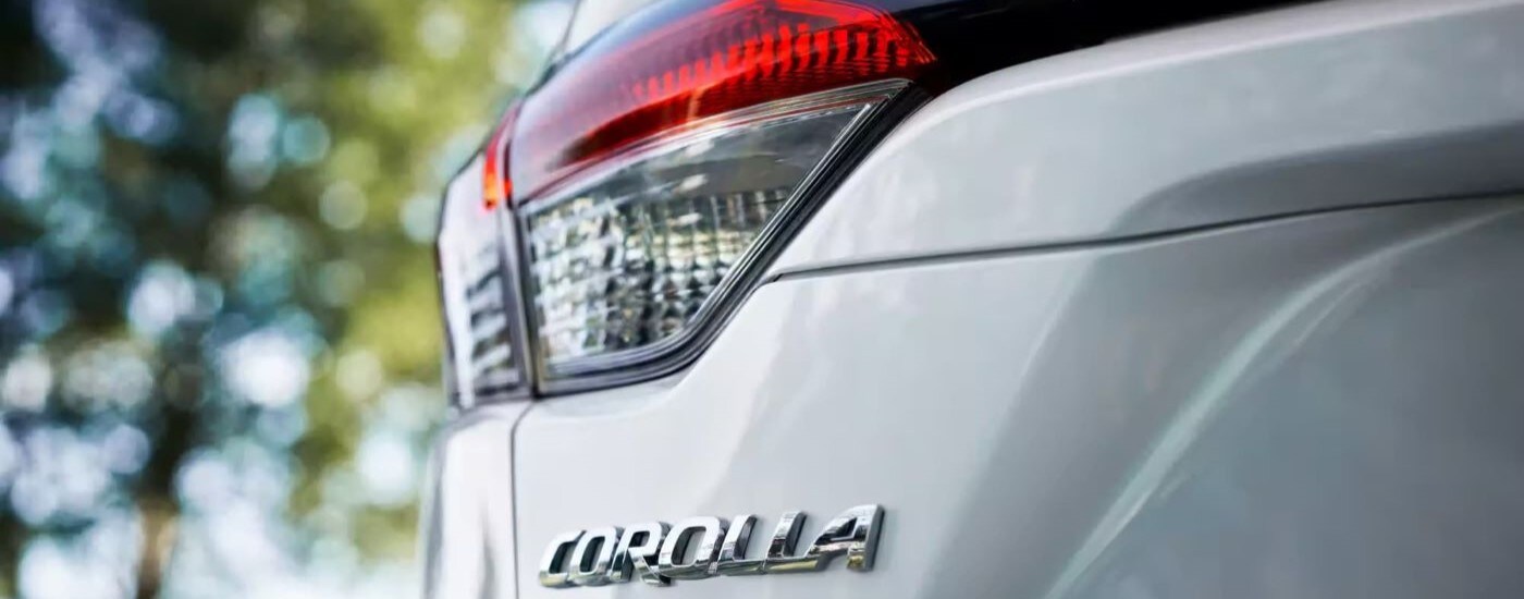 A close up shows driver side taillight on a white 2023 Toyota Corolla LE after leaving a car dealership.