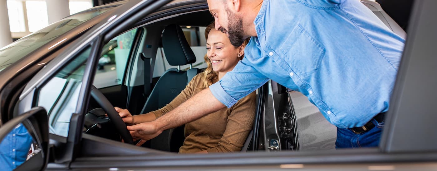A salesman is speaking to a woman at a car dealership.