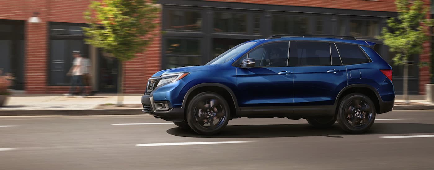 A blue 2020 Honda Passport Elite is shown from the side after leaving a used car dealership.