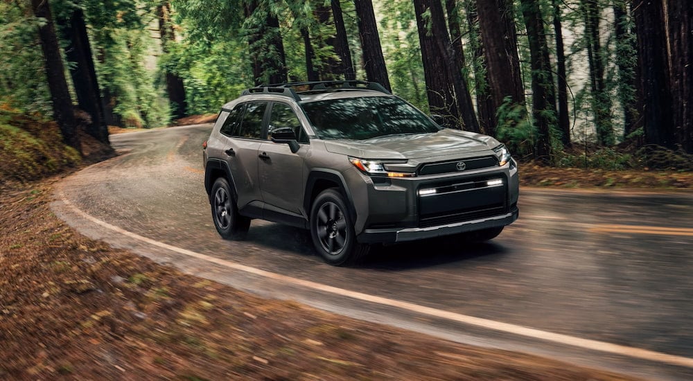 Grey 2026 Toyota RAV4 driving through a forest from a dealer with cars for sale near Morrisville.