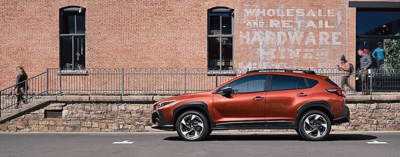 An orange 2024 Subaru Crosstrek parked near a hardware store.
