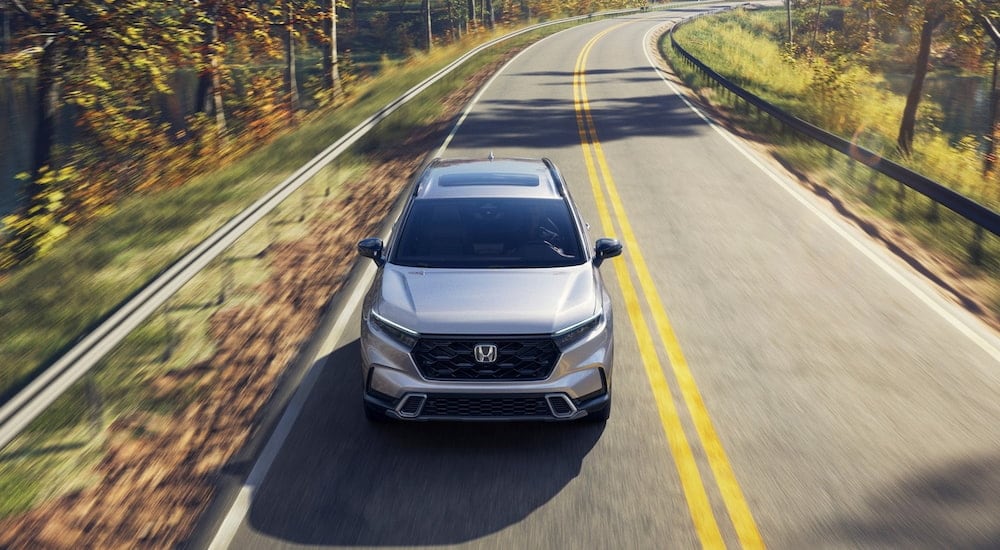 White 2026 Honda CR-V Sport Touring driving around a bend.