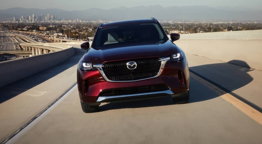 A red 2025 Mazda CX-90 driving to a car dealer near Alpharetta.