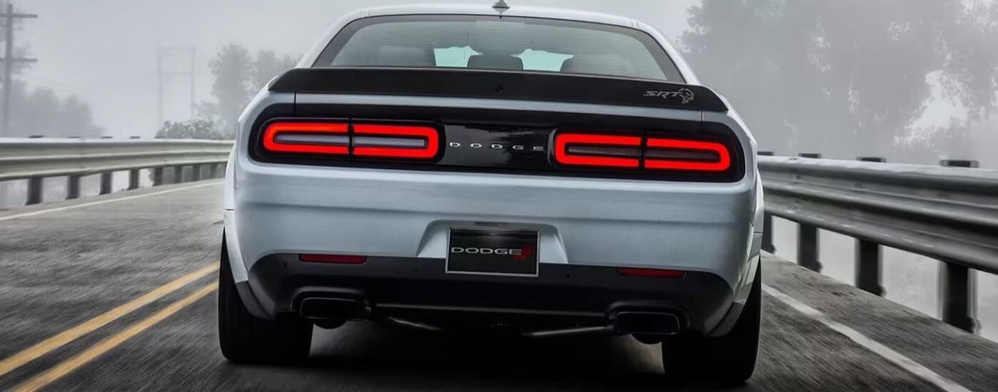 A silver 2023 Dodge Challenger SRT is shown from the rear driving through fog.
