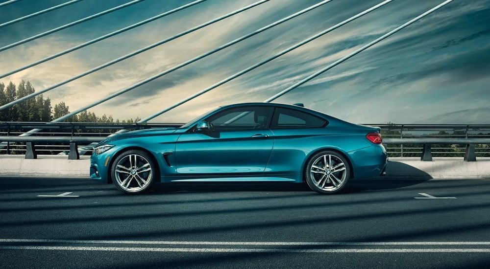 A blue 2019 BMW 4 Series is shown from the side parked on a bridge.