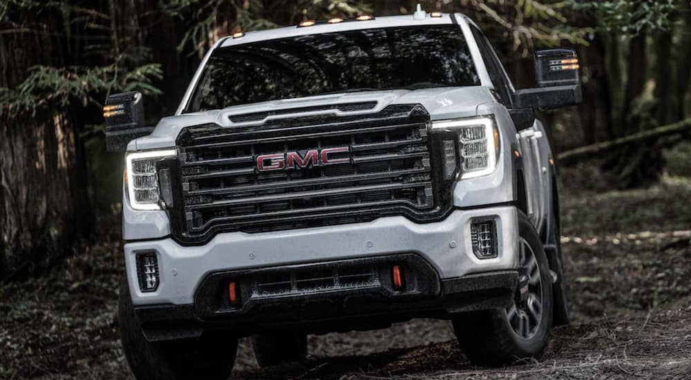White 2024 GMC Sierra 2500 HD AT4 driving through a forest.