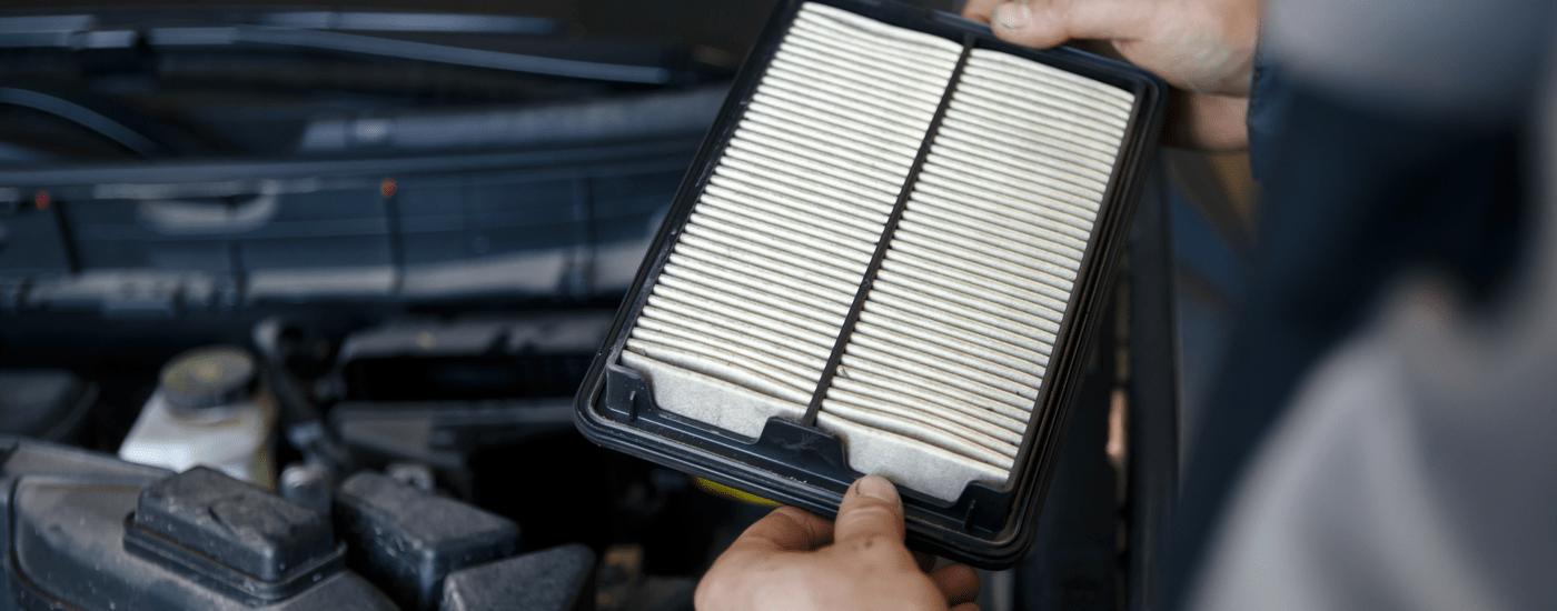A mechanic is replacing a vehicle's air filter.