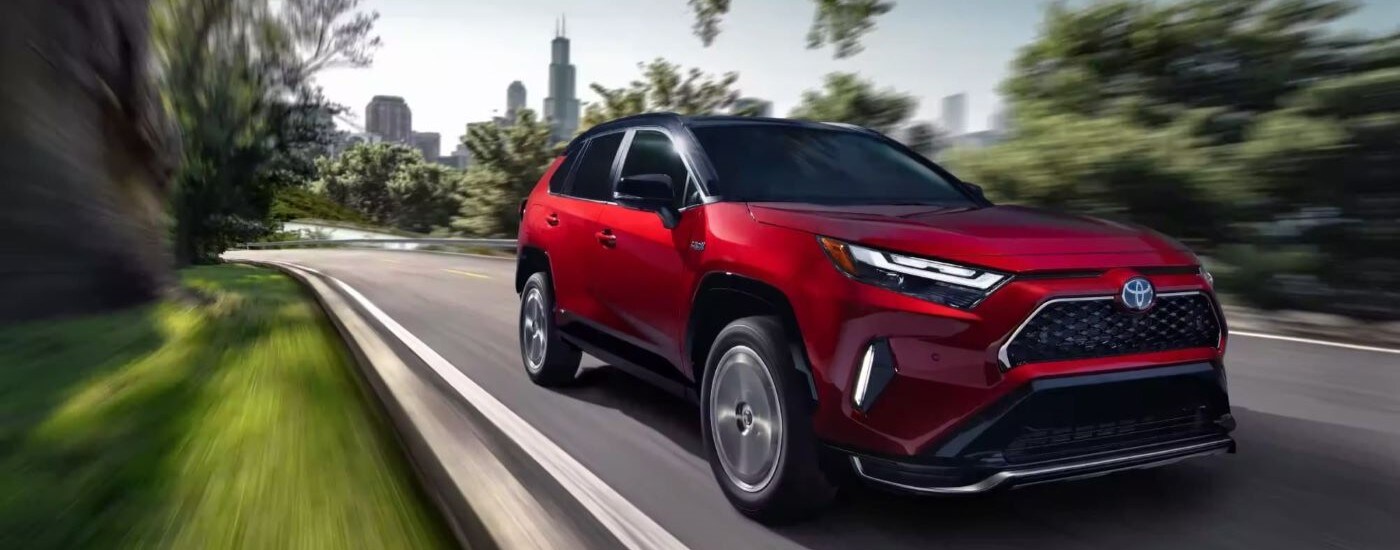  A red 2023 Toyota RAV4 Prime is shown driving near a city.
